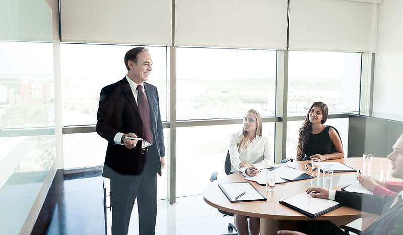 Ein sonnendurchflutetes Büro: Ein eloquenter Mitarbeiter der Avales Wilhelm führt ein Gruppen-Coaching durch.