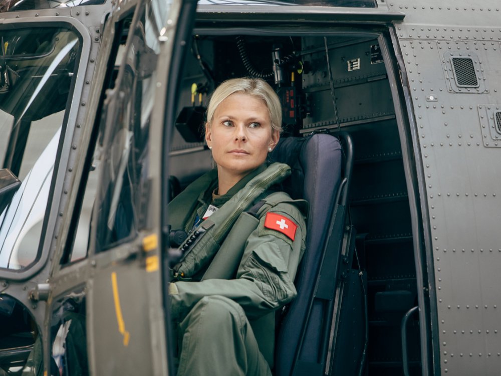 Junge blonde Frau sitzt im Cockpit eines Kleinflugzeugs. Sie trägt einen Pilotendress. Symbolisches Bild für Assessment Tools.